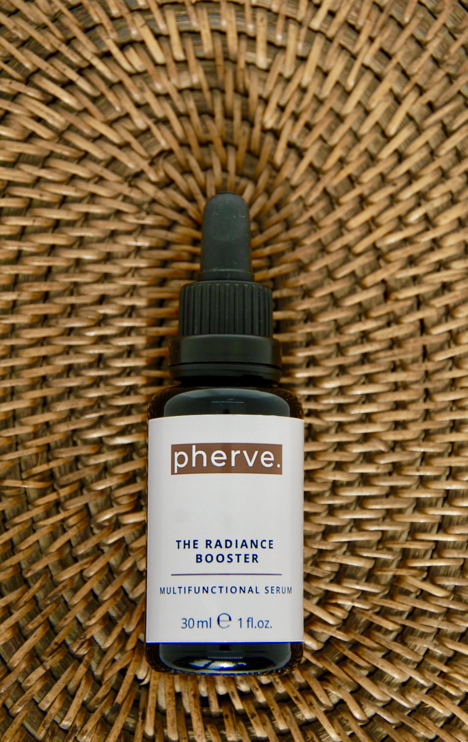 Image of the Radiance Booster serum bottle on a wooden background to amplify its multiple skin benefits