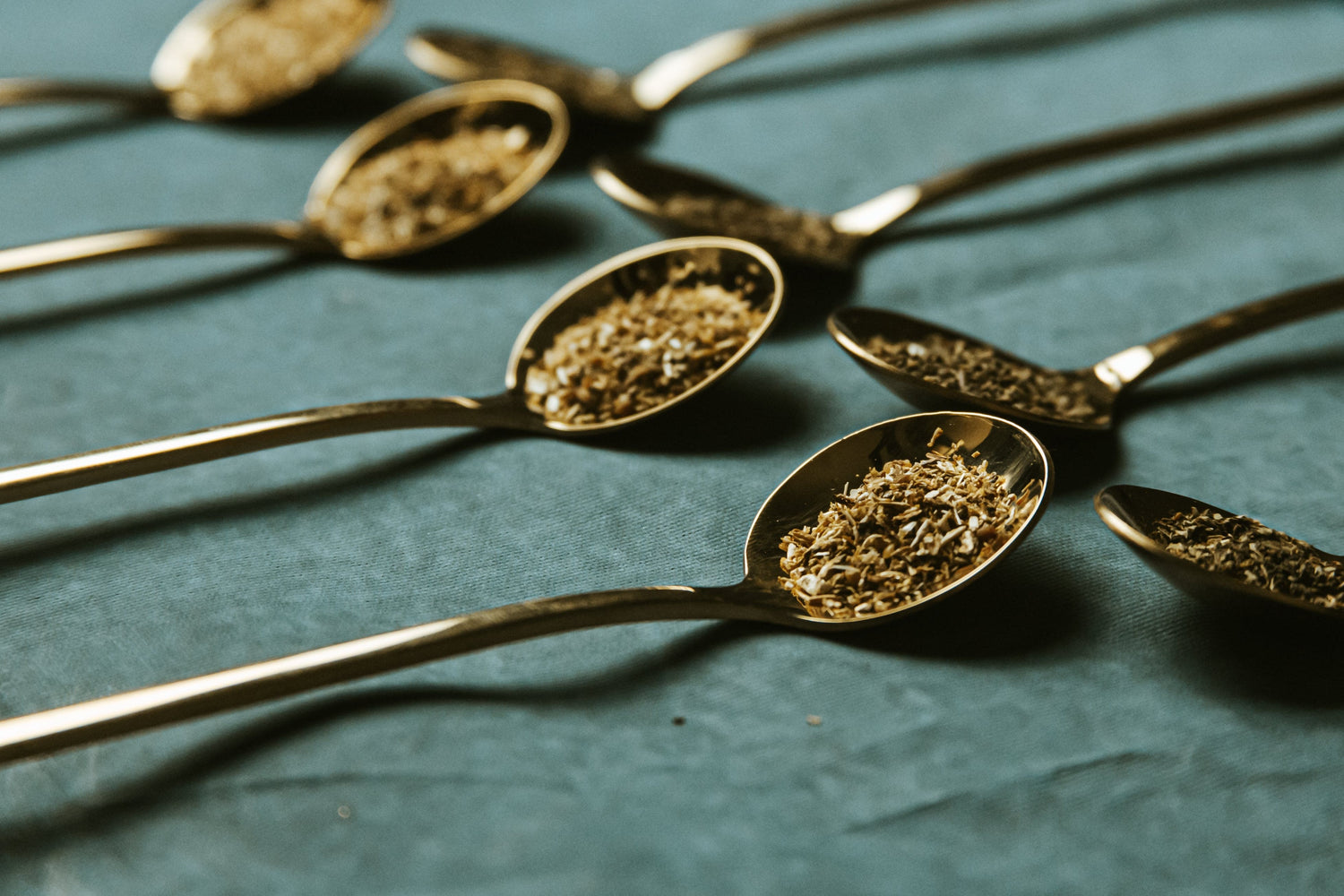 Immagine di una serie di cucchiai contenenti foglie di tè