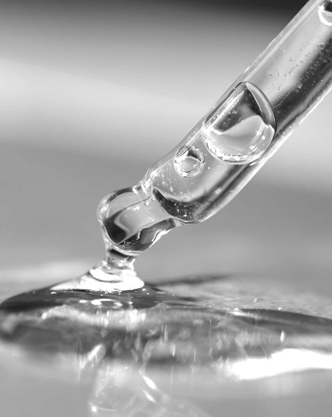 Multifunctional serum coming out from a transparent pipette. Black and white image.